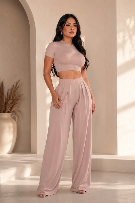 Mujer usando el conjunto Palazzo Wazary (top y pantalón) en tono rosa palo.